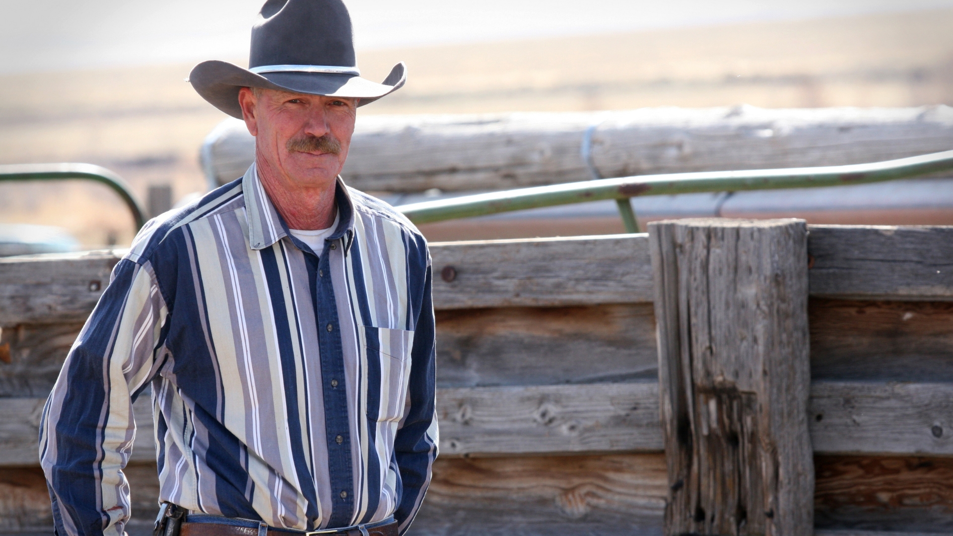 Rural rancher standing by wooden fencing